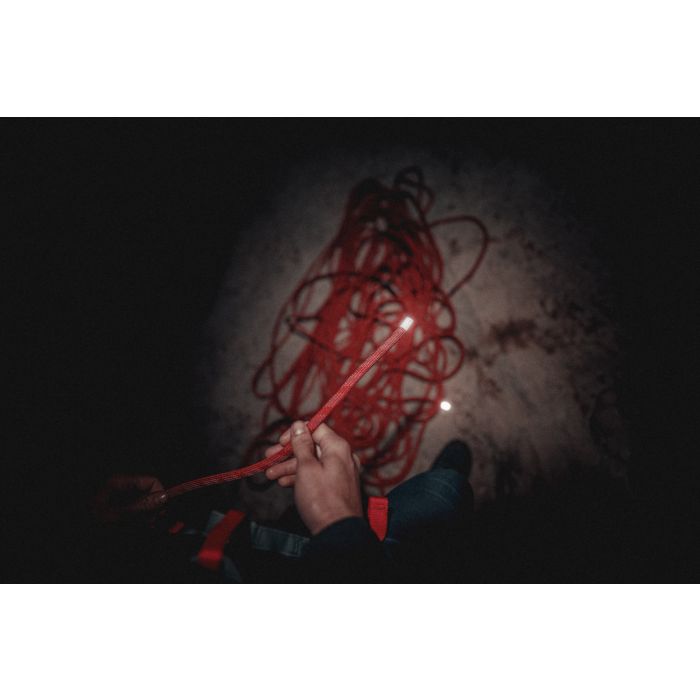 Hand holding a red cord against a dark background