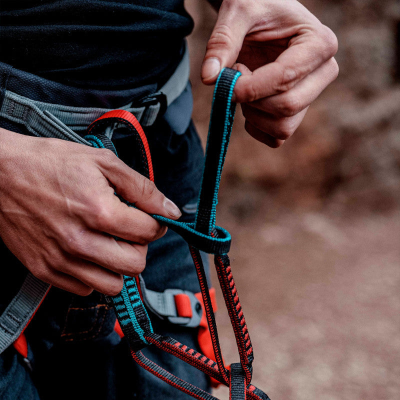 Person tying a knot with a blue and red rope in an outdoor setting