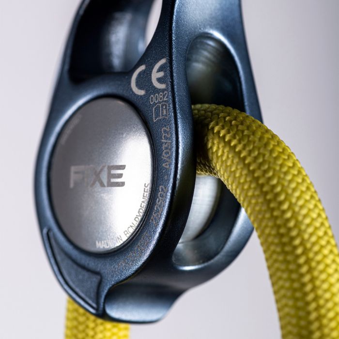 Close-up of a climbing device with yellow rope on a light gray background